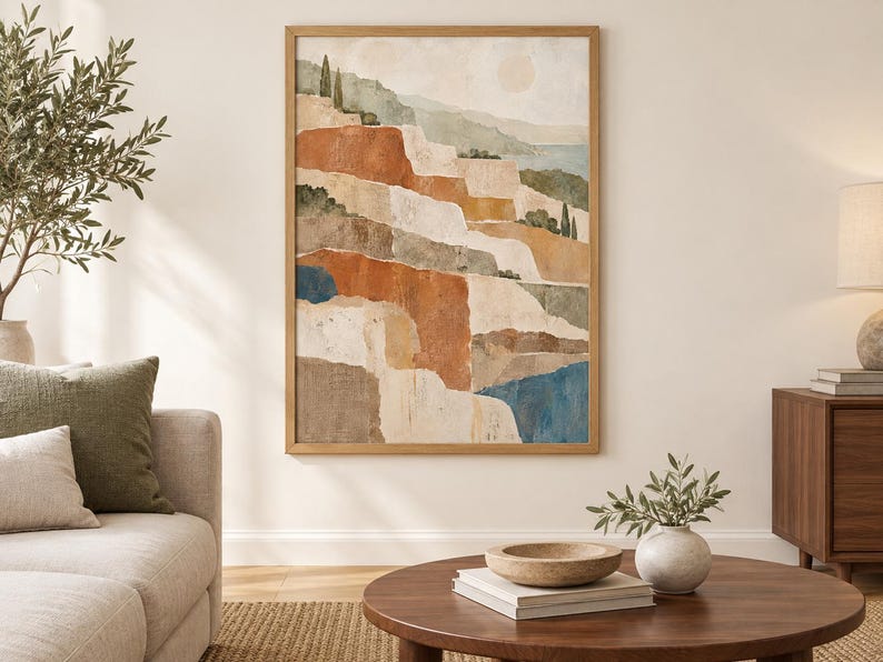 Op de afbeelding: Een verticale rechthoekige wandkunstprint in een lichthouten lijst met een abstract landschapsschilderij. De compositie toont gelaagde terrassen in tinten terracotta, cr&egrave;me, beige en gedempt blauw, geaccentueerd door kleine groene bomen.