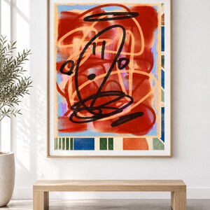 K&ouml;nnte beinhalten: Ein gerahmtes, rechteckiges Wandbild mit einer zentralen Komposition aus kr&auml;ftigen schwarzen Kritzeleien, die &uuml;ber abstrakten roten, orangefarbenen und hellblauen Formen liegen. Der untere Rand zeigt ein Muster aus vertikalen gr&uuml;nen, blauen und orangefarbenen Streifen.