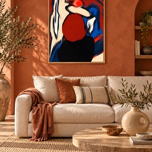 May include: A framed abstract wall art piece featuring bold, expressive brushstrokes in vibrant red, deep blue, black, and cream tones. The composition displays a central red circular form set against contrasting dark and light color blocks.
