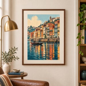 May include: A framed wall art print depicting a coastal town with colorful buildings in shades of orange, yellow, and blue, situated along a waterfront. A small wooden boat floats on the water, which reflects the vibrant architecture and sky.