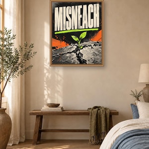 May include: A rectangular wall art print featuring the word MISNEACH in bold white capital letters. Below the text, a small green sprout emerges from a cracked gray surface. The background includes black textured patterns and bright orange accents.