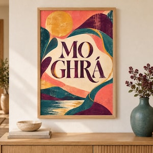 May include: A rectangular framed wall art print featuring the text MO GHR&Aacute; in dark purple serif lettering. The artwork displays a stylized landscape with a golden sun, rolling hills in shades of teal, deep purple, and coral, and a reflective water surface.