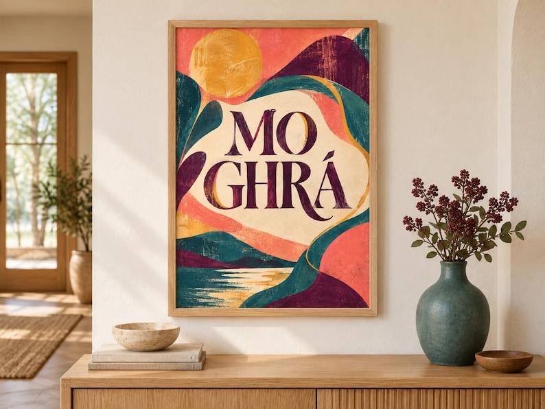 May include: A rectangular framed wall art print featuring the text MO GHR&Aacute; in dark purple serif lettering. The artwork displays a stylized landscape with a golden sun, rolling hills in shades of teal, deep purple, and coral, and a reflective water surface.