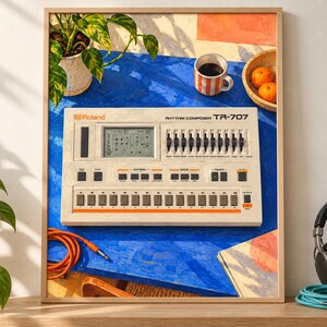 May include: A framed print featuring a Roland TR-707 Rhythm Composer drum machine. The device is off-white with black buttons, sliders, and a digital display. It sits on a bright blue surface alongside a coffee mug, oranges, and an orange cable.