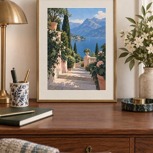 Peut inclure: Une impression d'art encadr&eacute;e repr&eacute;sentant un escalier en pierre menant vers un lac bleu et des montagnes, dans un cadre dor&eacute; fin. La sc&egrave;ne pr&eacute;sente des pots en terre cuite, un feuillage vert luxuriant et des cypr&egrave;s sous un ciel bleu.