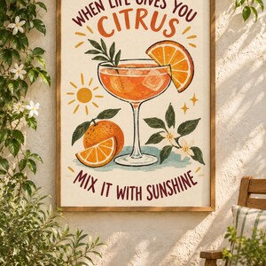 May include: A framed wall art print featuring a cocktail glass filled with an orange liquid, ice cubes, and an orange slice garnish. The text reads, "WHEN LIFE GIVES YOU CITRUS MIX IT WITH SUNSHINE." Includes illustrations of a whole orange and blossoms.