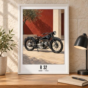Puede incluir: Una l&aacute;mina de arte enmarcada que muestra una motocicleta BMW R 32 negra de 1923. La motocicleta est&aacute; estacionada sobre una superficie pavimentada frente a una pared roja. El texto R 32 y BMW 1923 est&aacute; impreso en negro en el borde inferior.
