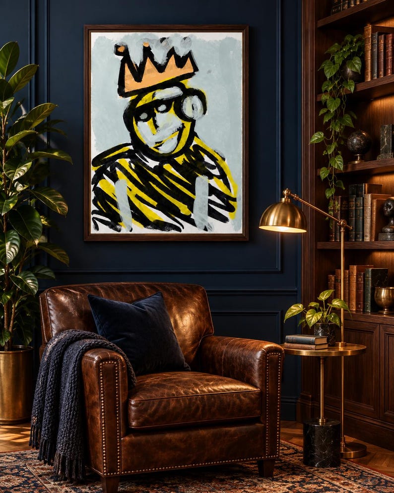 May include: A rectangular framed wall art piece featuring a stylized, abstract portrait of a figure wearing a peach-colored crown. The artwork uses bold, expressive black and yellow brushstrokes against a light blue background, set in a dark frame.