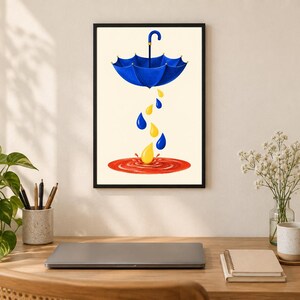 Pu&ograve; includere: Una stampa d'arte incorniciata raffigurante un ombrello blu sospeso in aria. Sotto l'ombrello, diverse gocce di pioggia blu e gialle cadono verso una pozzanghera rossa circolare a terra, creando un effetto di schizzo al centro.