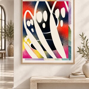 May include: A framed abstract wall art print featuring a vibrant, spray-painted background with gradients of red, yellow, blue, and purple. Overlaid on the colorful base are bold, smooth, cream-colored organic shapes and curved lines.