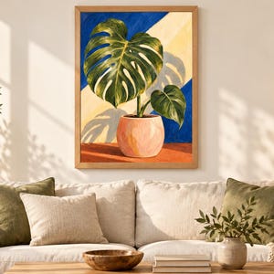 Puede incluir: Un cuadro enmarcado de una planta monstera verde en una maceta rosa claro. El fondo presenta rayas diagonales de color azul oscuro y amarillo p&aacute;lido, con una superficie naranja oscuro bajo la maceta y una sombra proyectada por las hojas.