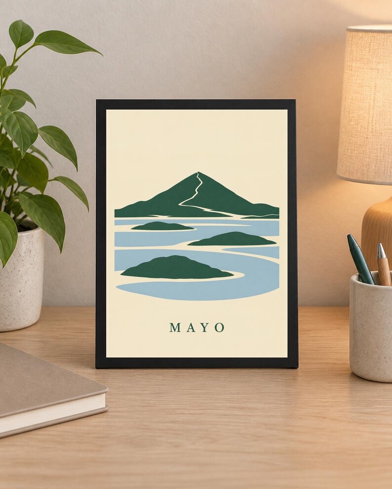 Pu&ograve; includere: Una stampa rettangolare incorniciata che presenta un'illustrazione paesaggistica stilizzata di una montagna e isole verde scuro su uno sfondo d'acqua azzurro in un campo color crema, con la parola MAYO stampata in verde scuro in basso.