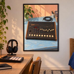 K&ouml;nnte beinhalten: Ein gerahmter Wandkunstdruck einer vintage LinnDrum elektronischen Drum-Machine. Das Ger&auml;t ist schwarz mit Holzseitenteilen und verf&uuml;gt &uuml;ber eine Digitalanzeige, mehrere Schieberegler und quadratische Tasten. Es steht auf einer hellblauen Oberfl&auml;che mit einem aufgerollten schwarzen Kabel und einer kleinen Topfpflanze, beleuchtet von warmem, nat&uuml;rlichem Sonnenlicht.