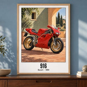 May include: A framed wall art print featuring a red Ducati 916 motorcycle parked on a terracotta patio. The text 916 and Ducati 1994 is printed in black at the bottom. The background shows a Mediterranean-style building with an archway.