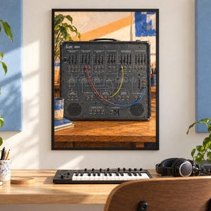 May include: A framed wall print featuring a black ARP 2600 analog synthesizer with a complex interface of sliders, knobs, and patch points. The synthesizer is connected with red, yellow, and blue patch cables and sits on a wooden surface.