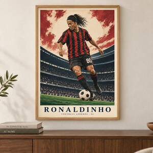 Pu&ograve; includere: Un poster incorniciato raffigurante un calciatore con maglia a righe rosse e nere e pantaloncini neri, che palleggia con un pallone su un campo. Lo sfondo mostra uno stadio sotto un cielo rosso. Il testo recita RONALDINHO FOOTBALL LEGENDS 80.