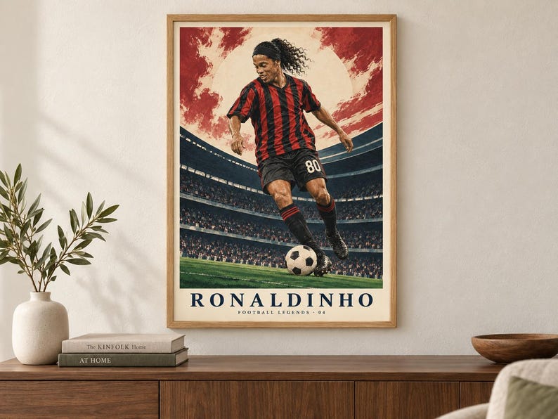 Pu&ograve; includere: Un poster incorniciato raffigurante un calciatore con maglia a righe rosse e nere e pantaloncini neri, che palleggia con un pallone su un campo. Lo sfondo mostra uno stadio sotto un cielo rosso. Il testo recita RONALDINHO FOOTBALL LEGENDS 80.