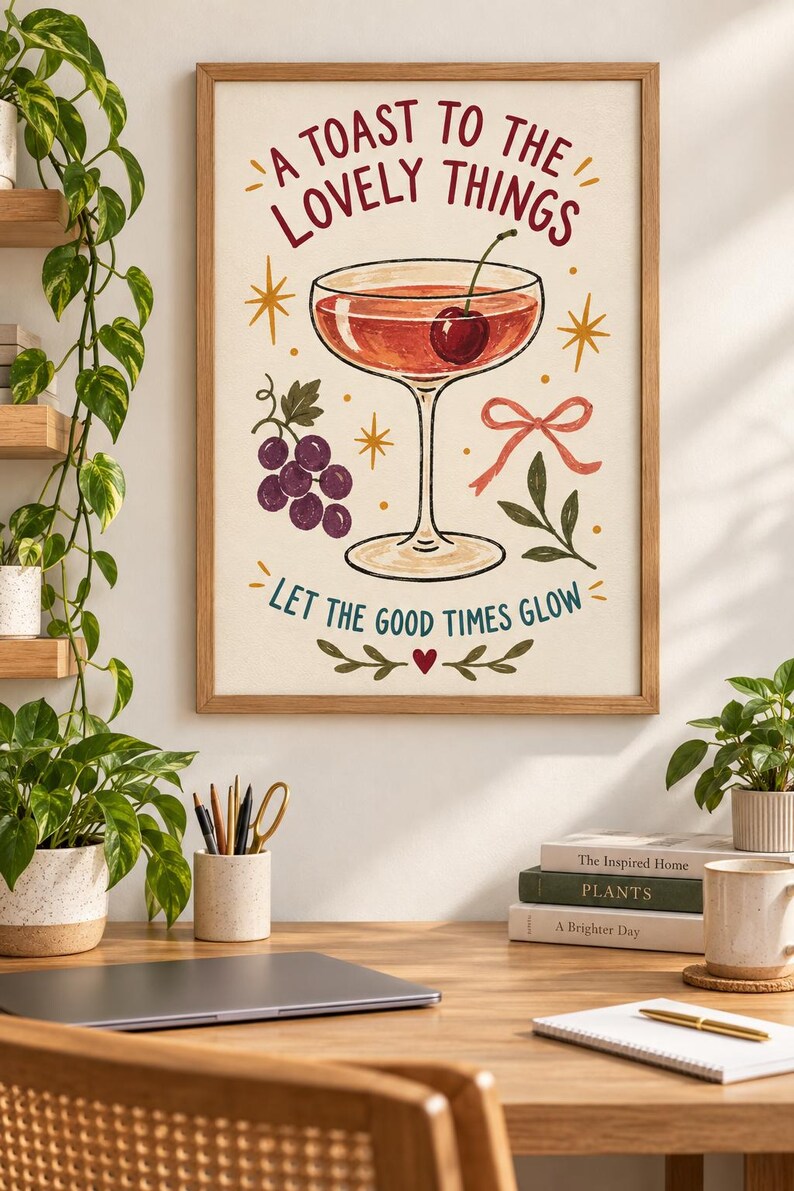 May include: A framed wall art print featuring a cocktail glass with a cherry, a cluster of purple grapes, and a pink ribbon. The text reads A TOAST TO THE LOVELY THINGS and LET THE GOOD TIMES GLOW, accented by yellow starbursts and a small red heart.