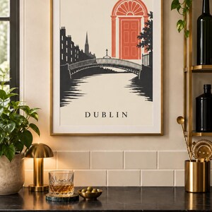 K&ouml;nnte beinhalten: Ein gerahmter Wandkunstdruck mit einer stilisierten schwarz-wei&szlig;en Illustration der Ha'penny Bridge in Dublin, Irland. Das Design enth&auml;lt eine markante orangefarbene T&uuml;r im georgianischen Stil und den Text DUBLIN unten in der Mitte.