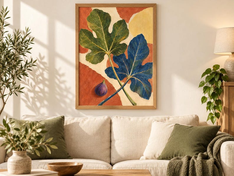 May include: A framed wall art print featuring a large green fig leaf and a large blue fig leaf overlapping on a background of abstract terracotta and cream shapes, with a single small purple fig fruit positioned in the lower left corner.