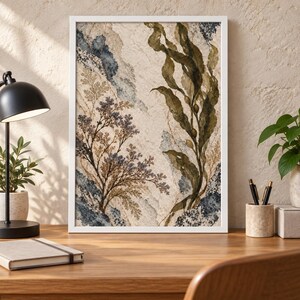 May include: A framed vertical wall art print featuring a botanical illustration with dark green seaweed, delicate brown fern-like foliage, and textured blue and cream abstract watercolor background elements within a simple white frame.