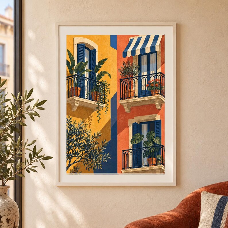 May include: A framed art print depicting a Mediterranean building facade with yellow and orange walls. The scene features three balconies with blue shutters, black railings, and potted plants. A striped blue and white awning covers one balcony.