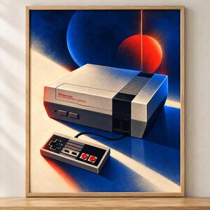 May include: A framed art print featuring a gray and black Nintendo Entertainment System console and a rectangular controller with a directional pad and two red buttons. The background displays a stylized cosmic scene with blue and red planets.