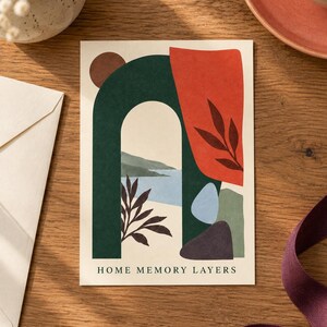 Pu&ograve; includere: Un biglietto d'auguri rettangolare con un'illustrazione astratta composta da un arco verde scuro, una forma rossa con sagome di foglie e un paesaggio costiero blu. Il testo HOME MEMORY LAYERS &egrave; stampato in nero sul fondo del biglietto color crema.