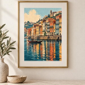 May include: A framed wall art print depicting a coastal town with colorful buildings in shades of orange, yellow, and blue along a stone embankment. A small wooden boat floats on the calm water, which reflects the vibrant architecture and blue sky.