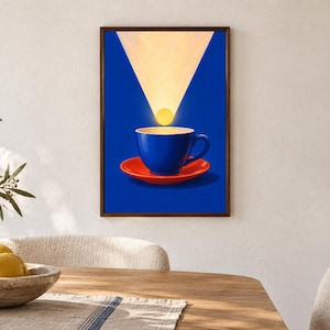 Puede incluir: Una l&aacute;mina de arte enmarcada que muestra una taza de caf&eacute; azul vibrante sobre un plato rojo brillante. Sobre la taza, un c&iacute;rculo amarillo brillante se sit&uacute;a dentro de un haz de luz triangular, sobre un fondo azul profundo.
