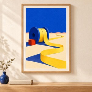 Op de afbeelding: Een ingelijste kunstdruk met een surrealistisch landschap met een grote blauwe spoel die een lang geel lint afrolt over een beige woestijnbodem. Een kleine rode kubus staat naast de spoel onder een effen blauwe lucht.