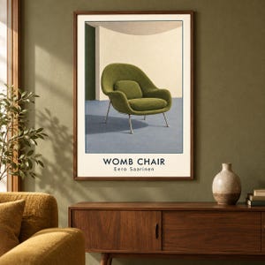 May include: A framed wall art print featuring a green Womb chair by Eero Saarinen. The illustration shows the chair on a blue floor against a curved cream wall. The text WOMB CHAIR and Eero Saarinen is printed in black at the bottom of the poster.