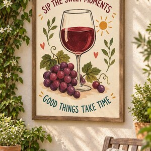 May include: A framed wall art print featuring a glass of red wine, a cluster of purple grapes, and green leaves. The text reads SIP THE SWEET MOMENTS at the top and GOOD THINGS TAKE TIME at the bottom, with a small yellow sun and red hearts.