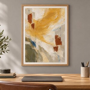 May include: A framed abstract wall art print featuring a textured composition of mustard yellow, burnt orange, olive green, and white paint strokes. The artwork is enclosed in a light-toned wooden frame with a white mat border, displayed on a wall.