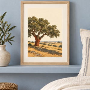 Op de afbeelding: Een ingelijste kunstdruk met een landschapsillustratie van een grote kurkeik met een roodbruine stam in een goudkleurig veld. De sc&egrave;ne toont glooiende heuvels, bomen in de verte en een klein huis onder een bleke cr&egrave;mekleurige lucht.