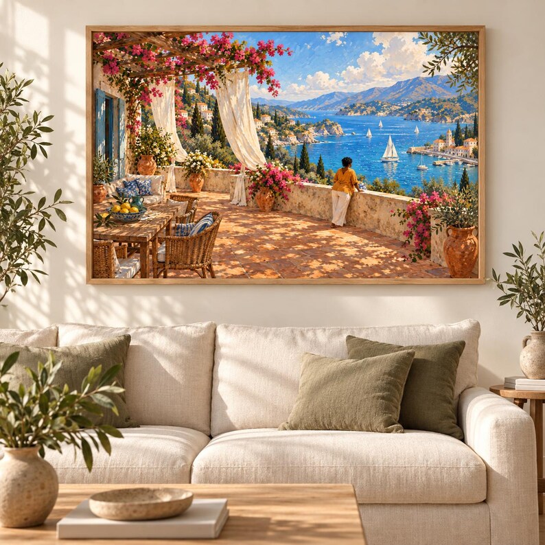 May include: A rectangular wall art print depicting a sunlit Mediterranean terrace with a stone floor, wicker furniture, and pink bougainvillea flowers. A person stands by a stone wall overlooking a blue bay with sailboats and distant mountains.