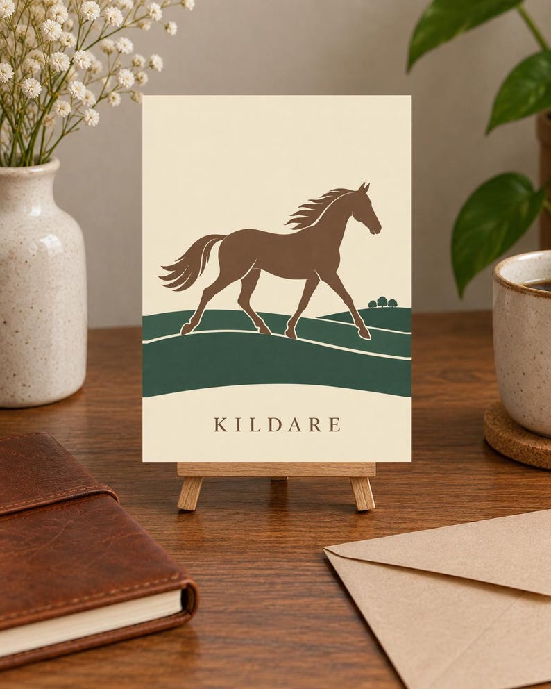 May include: A rectangular print on a small wooden easel featuring a brown horse silhouette galloping across dark green rolling hills against a cream background. The word KILDARE is printed in dark brown capital letters at the bottom of the print.