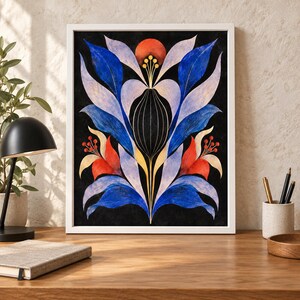 May include: A framed wall art print featuring a symmetrical botanical illustration on a black background. The design displays stylised blue, light purple, and red leaves and flowers with thin gold lines, all enclosed in a simple white frame.
