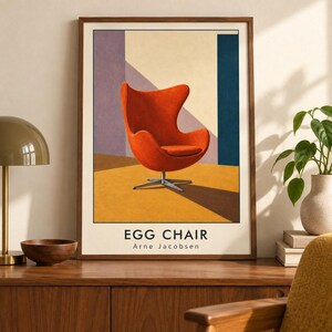 May include: A framed art print featuring a vibrant orange Egg Chair by Arne Jacobsen centred against a geometric background of purple, cream, and blue shapes on a yellow floor. The text EGG CHAIR Arne Jacobsen is printed in black at the bottom.