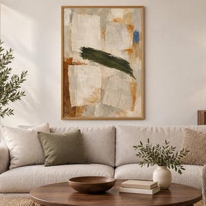 May include: A rectangular wall art piece in a light wood frame featuring an abstract composition. The artwork displays layered off-white rectangular shapes, warm ochre and brown tones, and a prominent, bold horizontal dark olive green brushstroke.