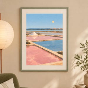 May include: A framed wall art print depicting a landscape of salt pans with rectangular pools of pink and blue water, a white salt mound, and a distant town under a clear blue sky with a pale yellow sun, enclosed in a sage green frame.