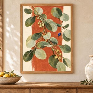 May include: A framed wall art print featuring a botanical illustration of a leafy branch with green foliage, small pale yellow buds, and a single dark blue berry, set against a vertical terracotta orange brushstroke on a cream background.