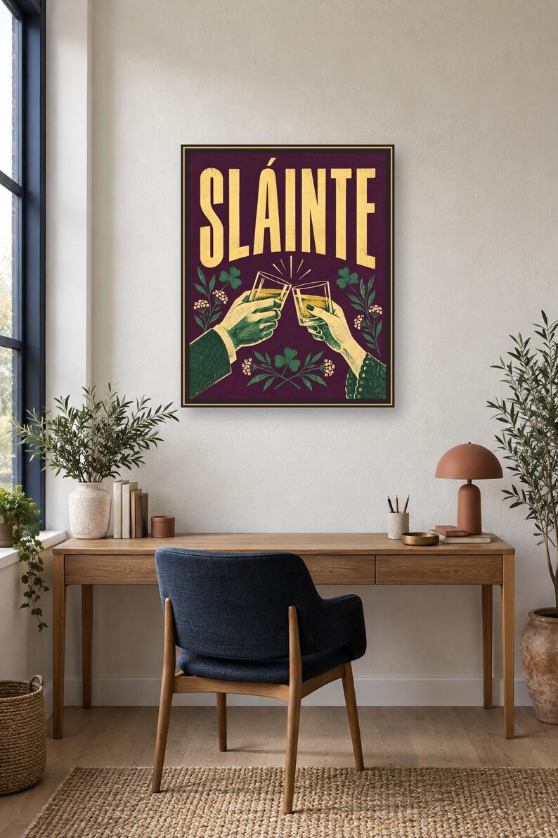 Pu&ograve; includere: Una stampa artistica da parete rettangolare con sfondo viola scuro e la parola SL&Aacute;INTE in grandi lettere gialle. L'illustrazione raffigura due mani che brindano con bicchieri pieni di un liquido dorato, circondate da foglie di trifoglio verdi e fiori bianchi.