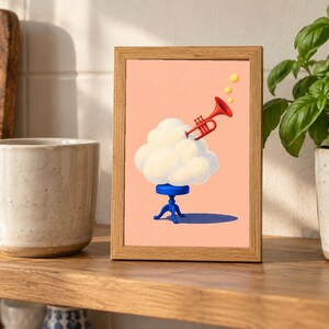 May include: A rectangular wooden frame containing a print on a peach background. The artwork depicts a white cloud resting on a small blue stool, with a red trumpet emerging from the cloud and three yellow circles floating above the trumpet.