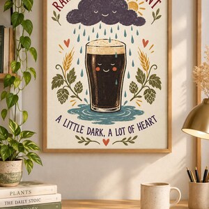 May include: A framed wall art print featuring a dark beer pint with a smiling face, surrounded by rain, a sun, and hop plants. The text reads: RAIN OR SHINE, HAVE A PINT and A LITTLE DARK, A LOT OF HEART, with red hearts and green foliage accents.
