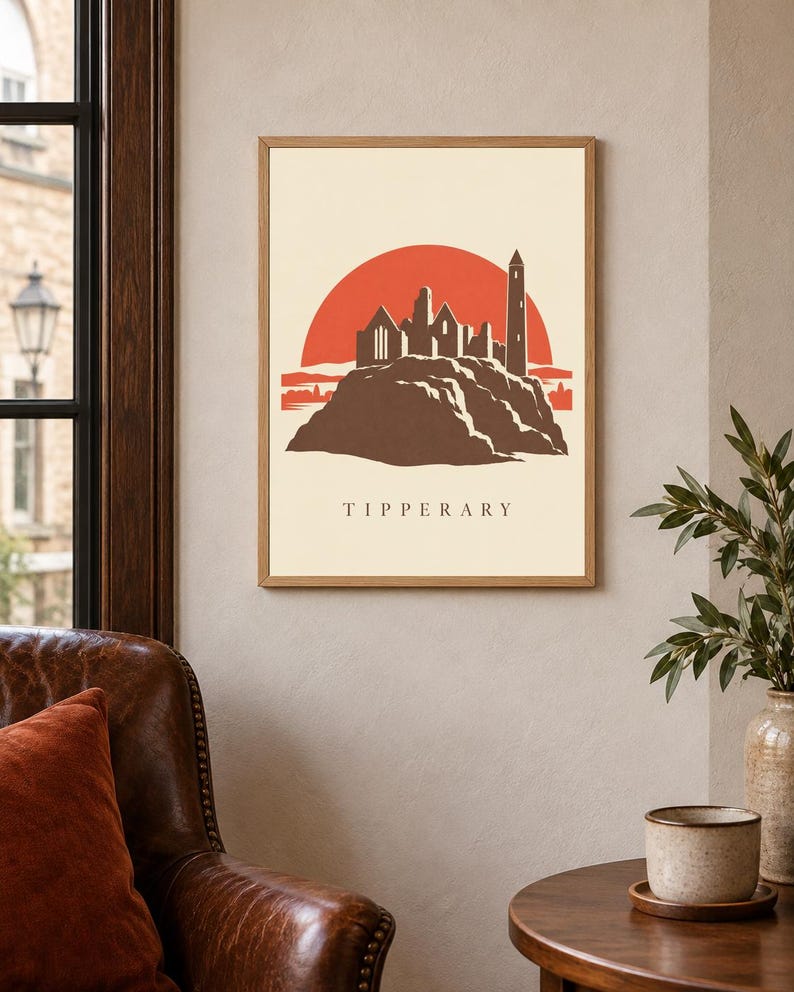 May include: A framed wall art print featuring a stylized illustration of the Rock of Cashel in Tipperary, Ireland. The design shows a brown silhouette of the stone ruins against a large, solid red sun on a cream background, with the text TIPPERARY.