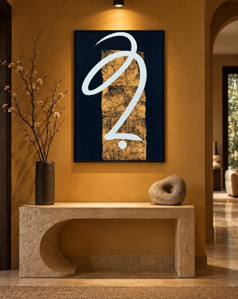 May include: A rectangular wall art piece featuring a dark navy blue background with a central vertical gold leaf panel and a large, fluid white calligraphic brushstroke shape that curves across the center, all enclosed in a thin black frame.