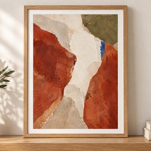 May include: A framed abstract wall art print featuring layered shapes in terracotta, cream, olive green, and a small accent of blue. The composition displays textured, organic forms with visible brushstroke details enclosed in a light wood frame.