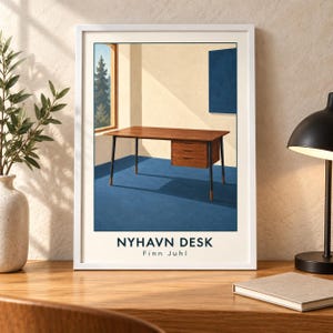May include: A framed art print featuring a wooden desk with three drawers and dark legs set in a room with blue flooring and a window view of trees. The text NYHAVN DESK and Finn Juhl is printed at the bottom of the white-bordered illustration.
