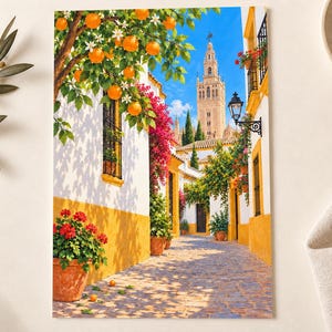 May include: A rectangular wall art print depicting a sunlit Mediterranean street scene with white buildings, yellow trim, and vibrant orange trees. A tall stone bell tower rises in the background under a clear blue sky, with terracotta pots of red flowers.